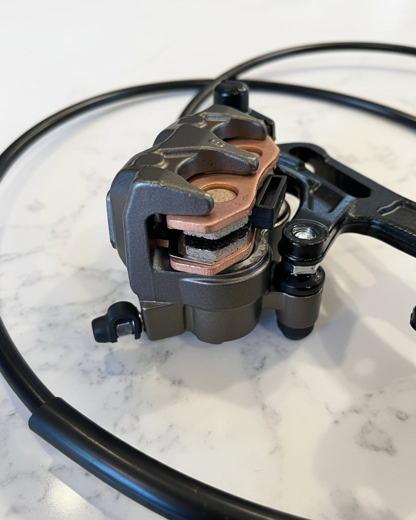 Surron Ultra Bee rear brake caliper close-up — pads visible