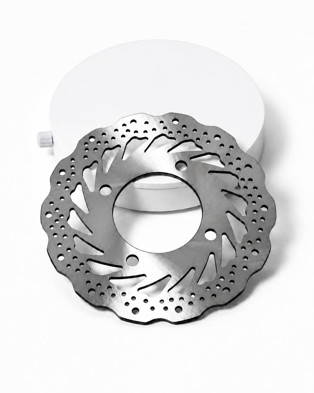 A silver metallic brake disc with a drilled and slotted pattern, shown in front of a white circular display stand on a white background. The black 'ER' logo is visible in the top-left corner.