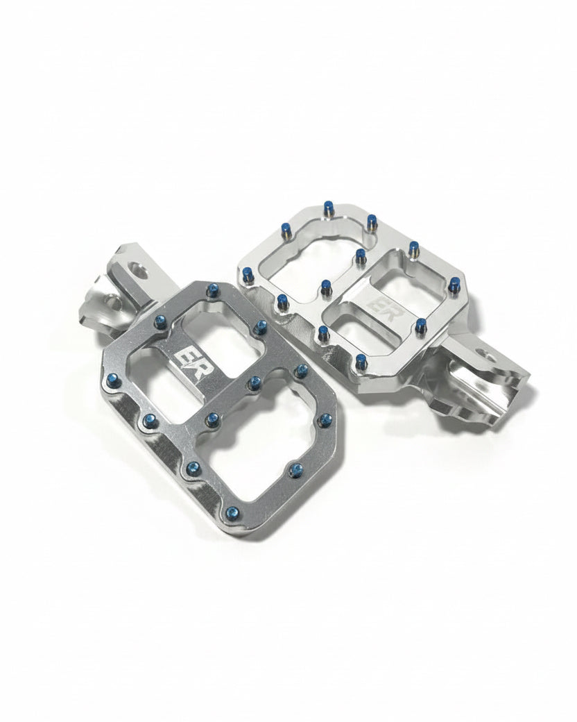 Pair of ER Moto ETM RTR super-wide footpegs in silver chrome CNC aluminum, blue titanium screws, ER logo engraving, angled top view

