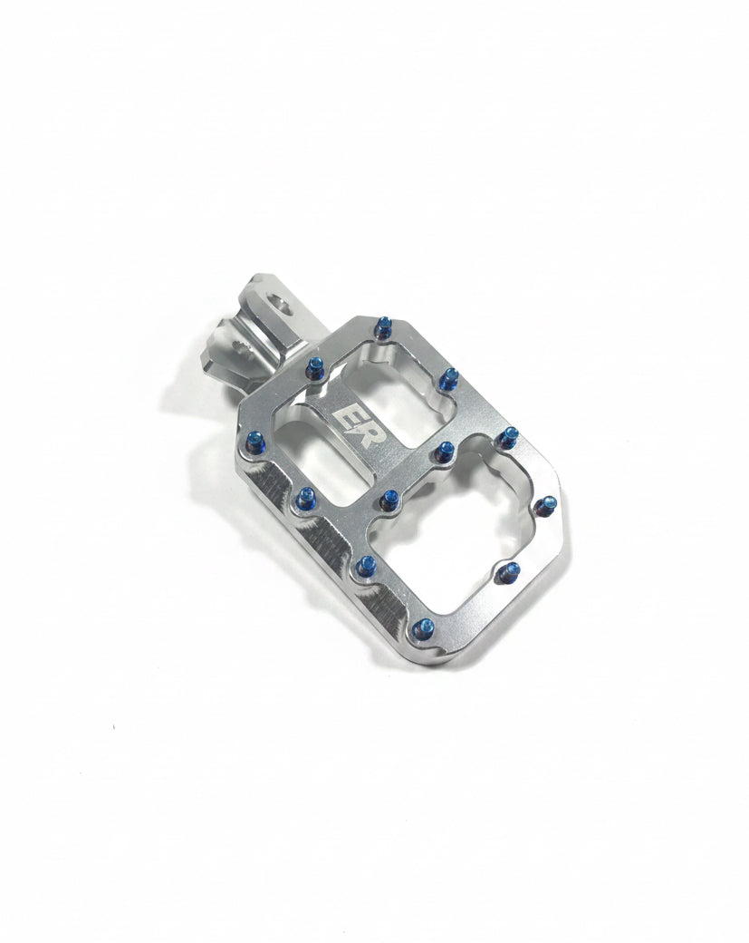 Close-up of aggressive grip teeth on ER Moto CNC footpegs for ETM RTR, burnt-blue titanium style screws